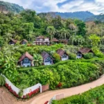 Aerial view of villas with peaked roofs set among tropical gardens and rainforest-covered hills at Oxygen Jungle Villas, Costa Rica