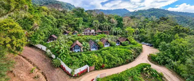 Aerial view of villas with peaked roofs set among tropical gardens and rainforest-covered hills at Oxygen Jungle Villas, Costa Rica